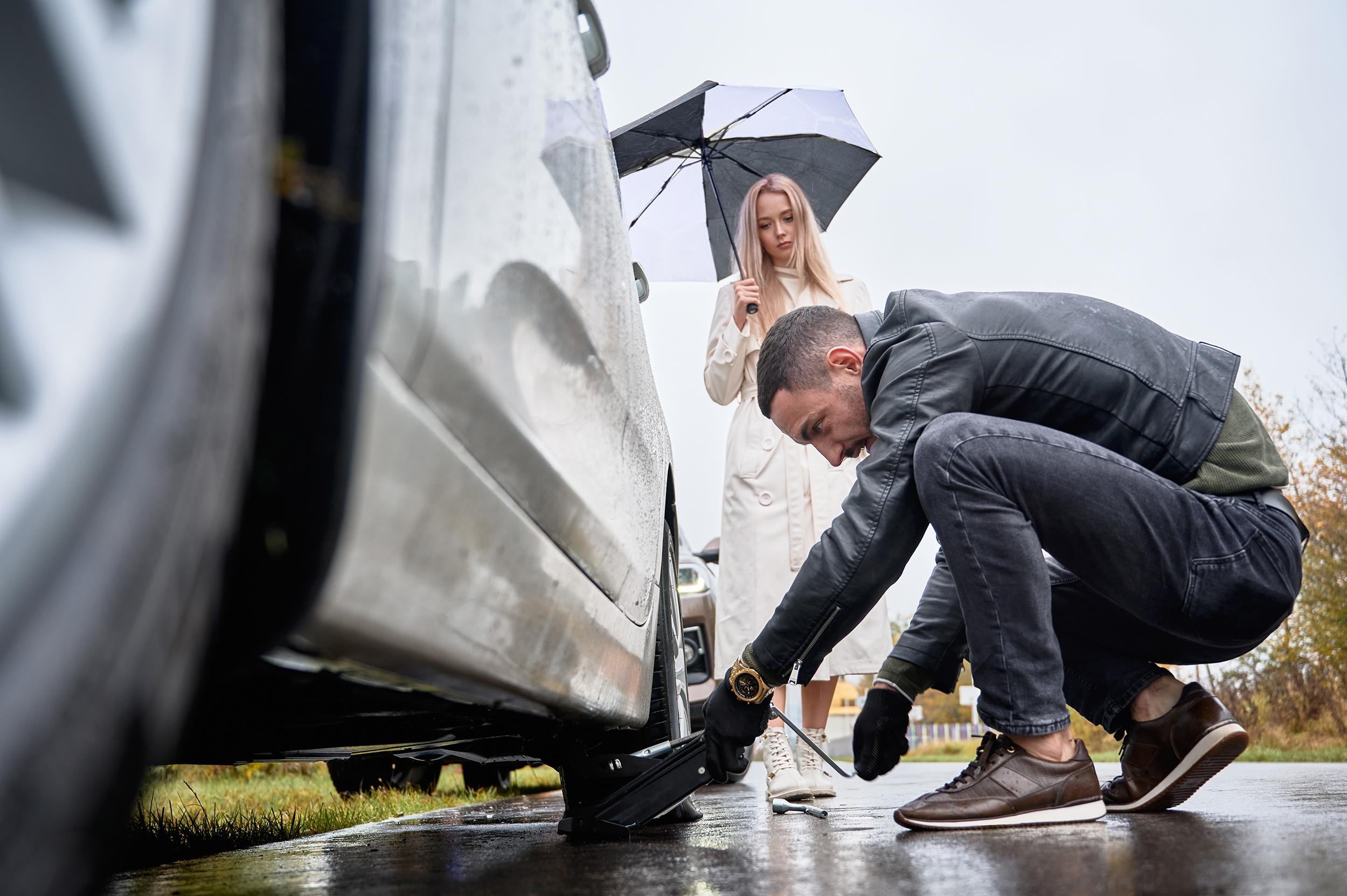 Young man helping beautiful woman to fix car on the road.